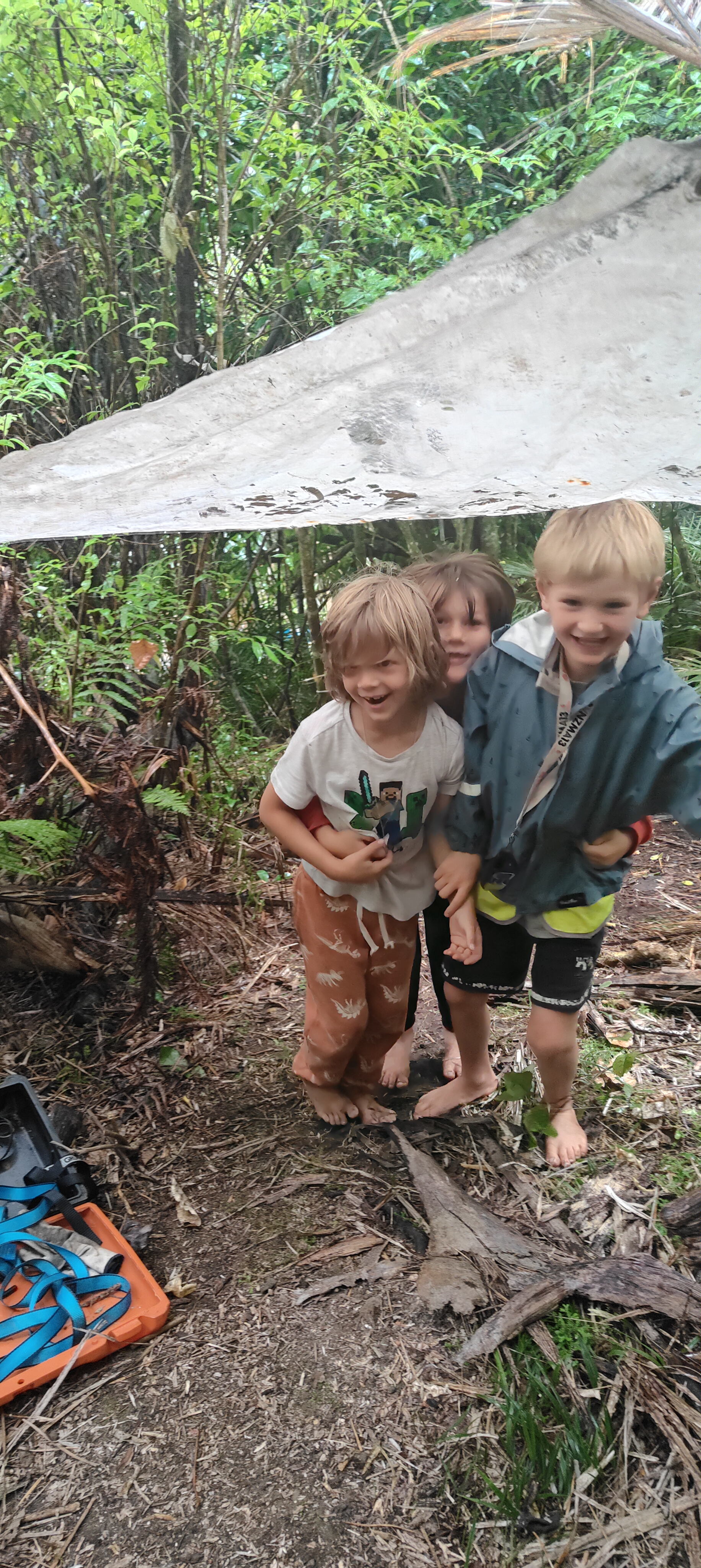 Three children laughing together in the native bush at The Bush Base