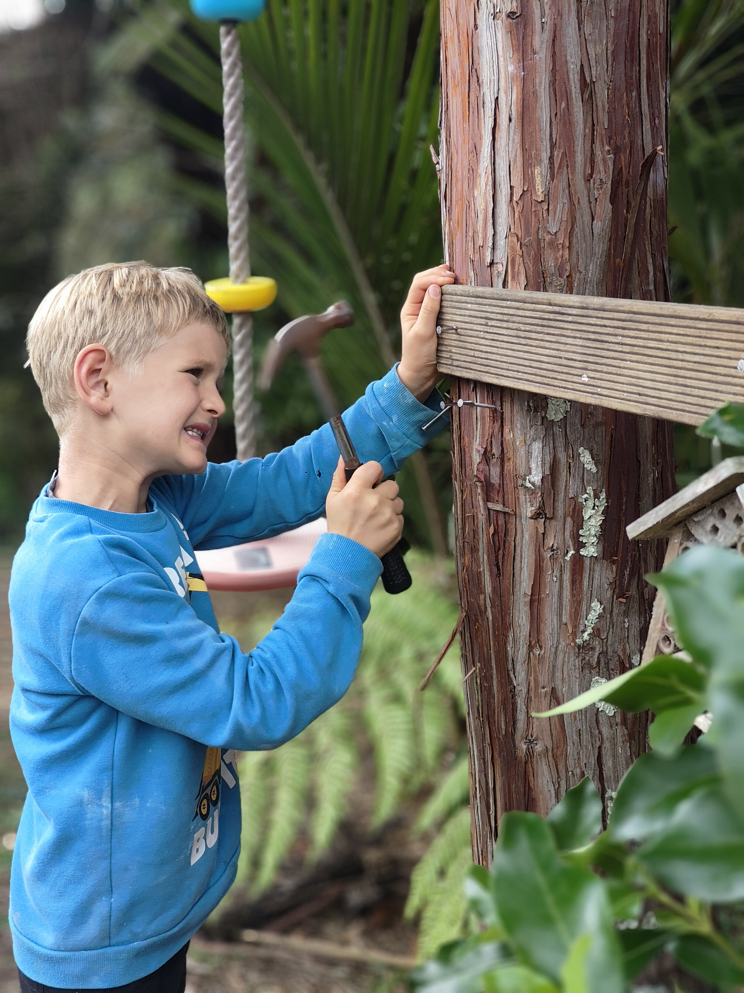 Child hammering nails into the tree structure