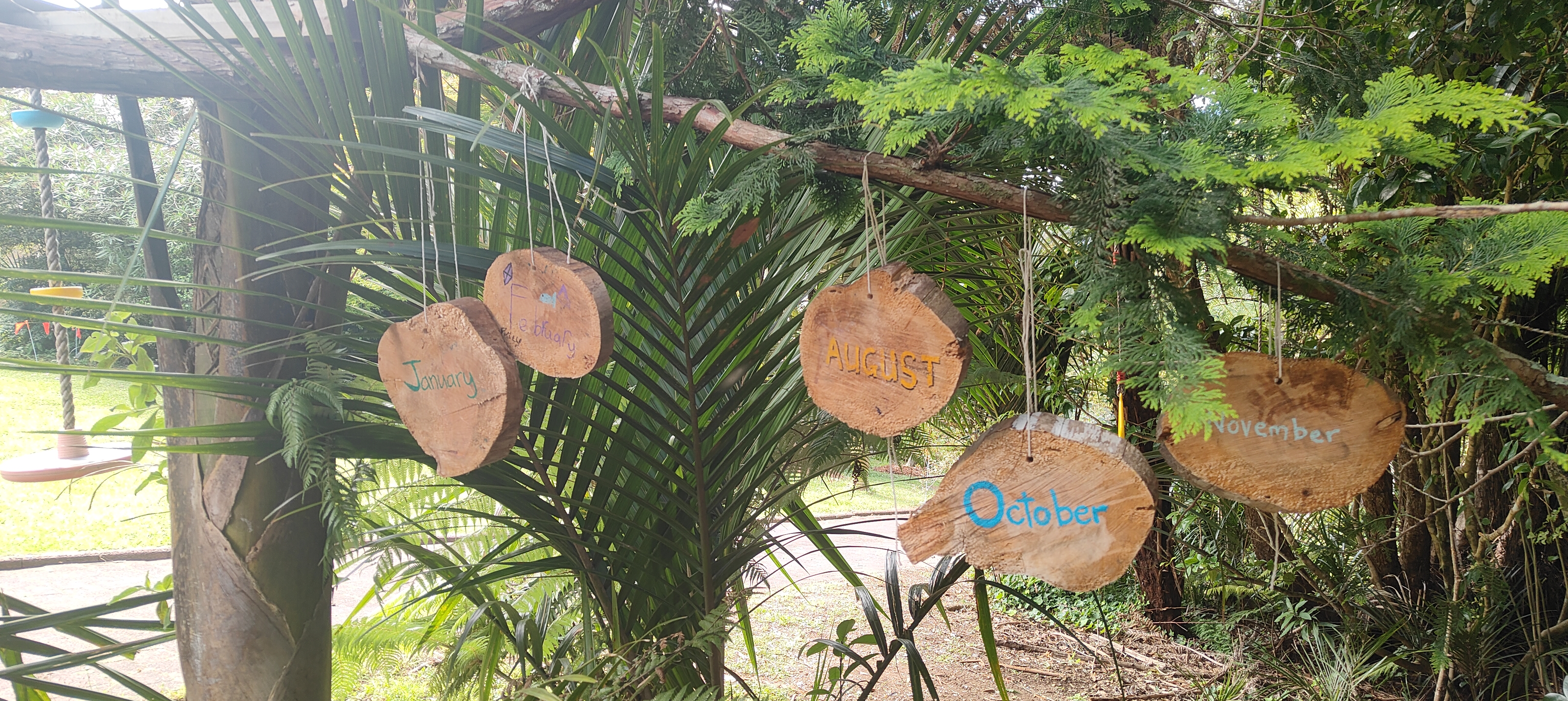 Hand-carved wooden month discs hanging in the garden