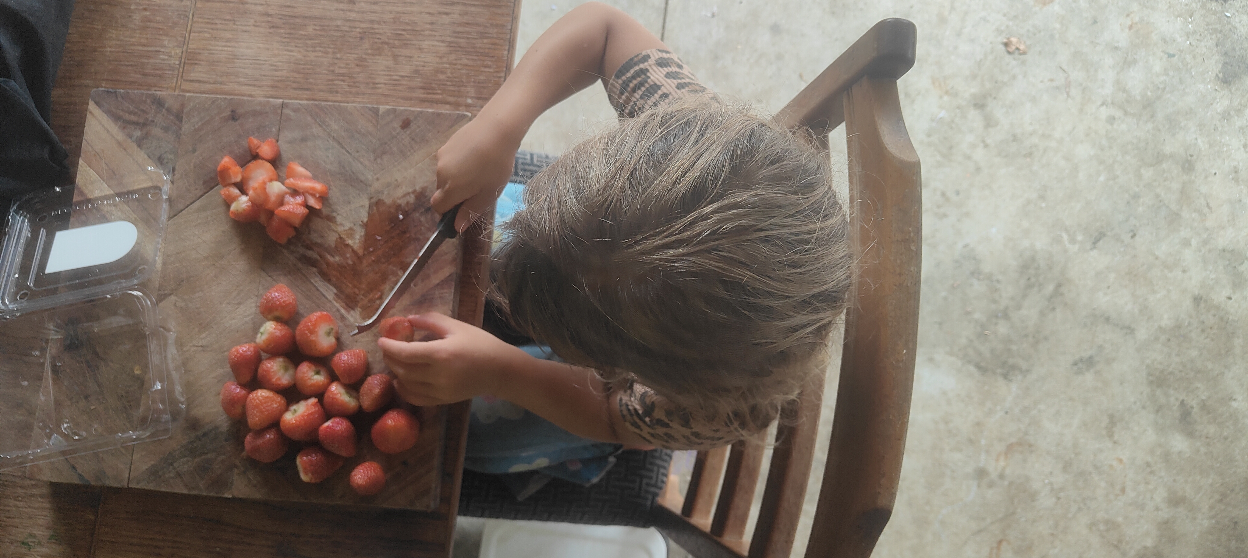 Child practising knife skills cutting strawberries